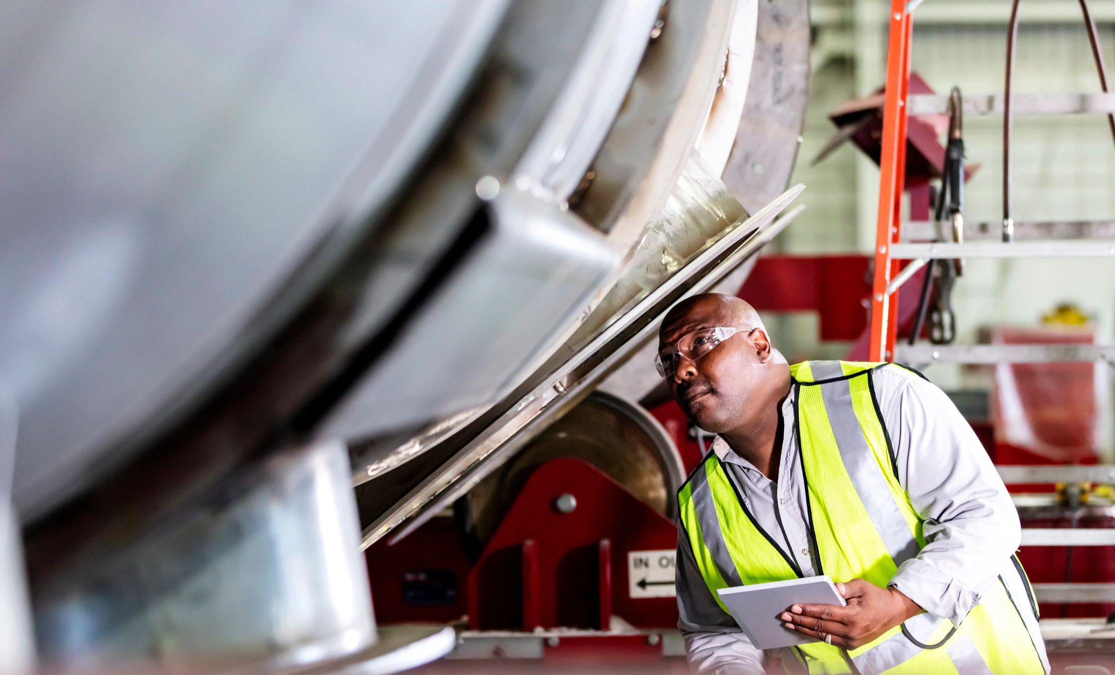 Engineer inspecting equipment with a tablet in a fabrication shop
