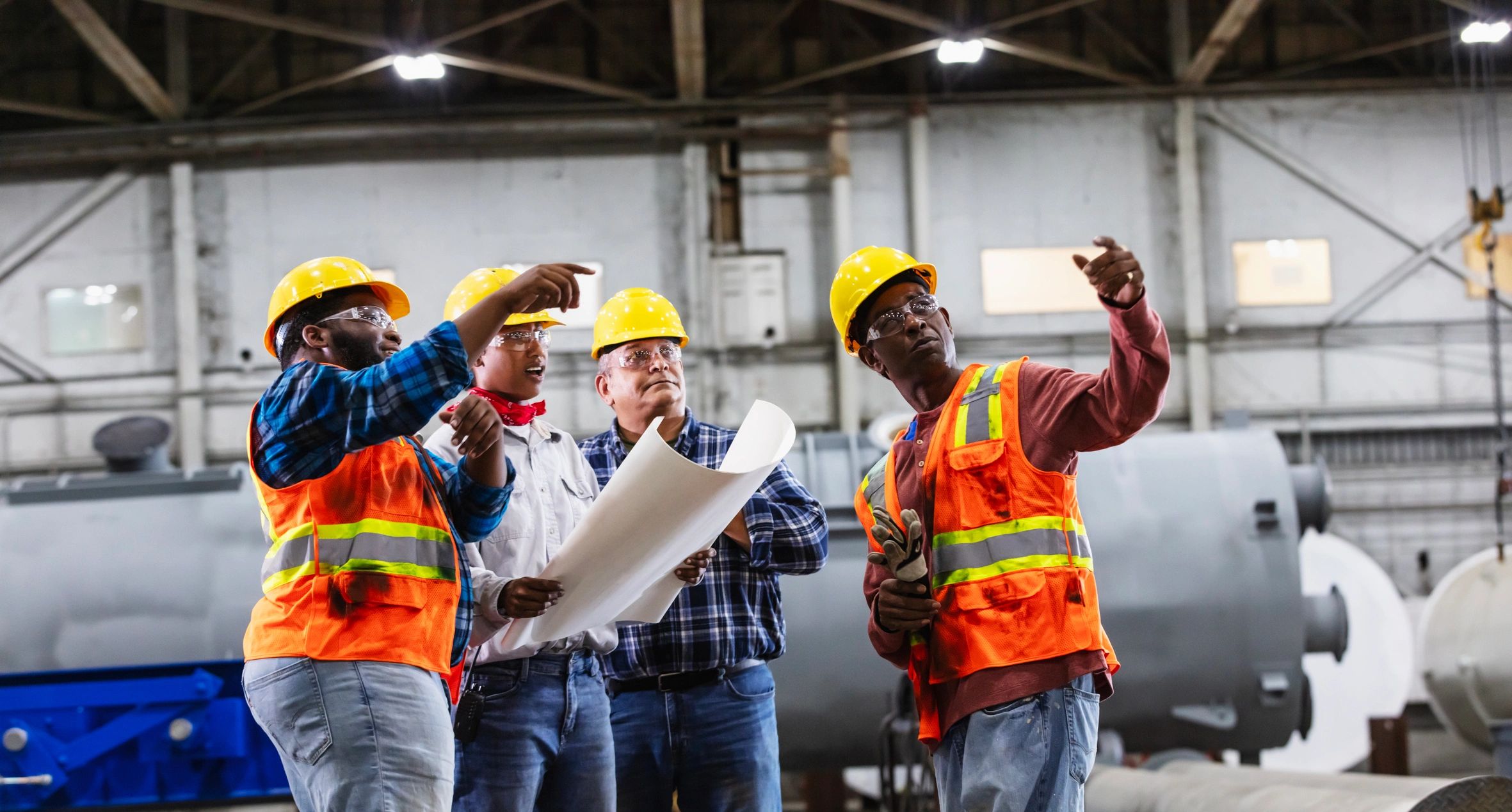 Engineers reviewing plans on a factory floor