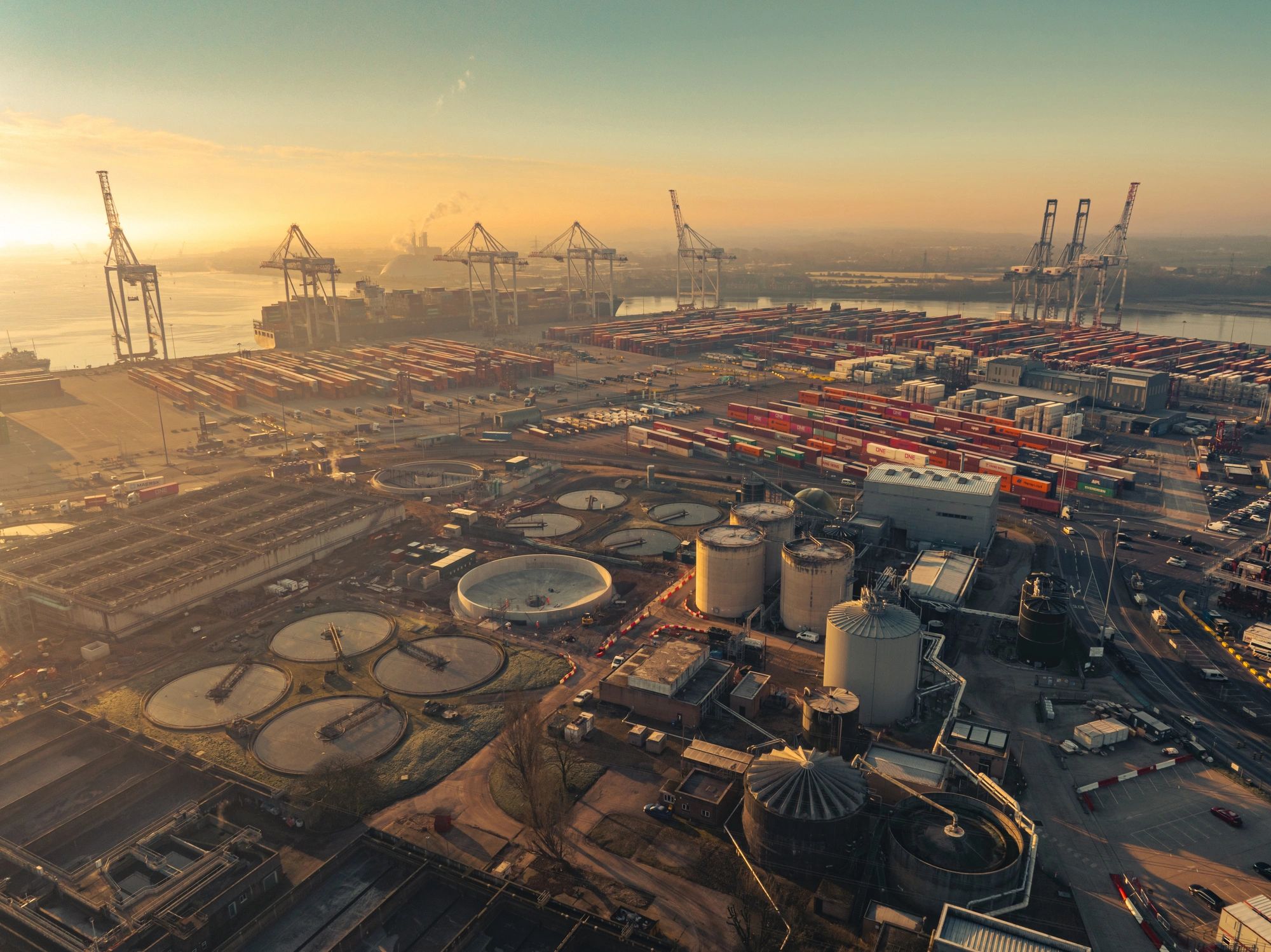 Gantry cranes and containers at an industrial port terminal at sunset