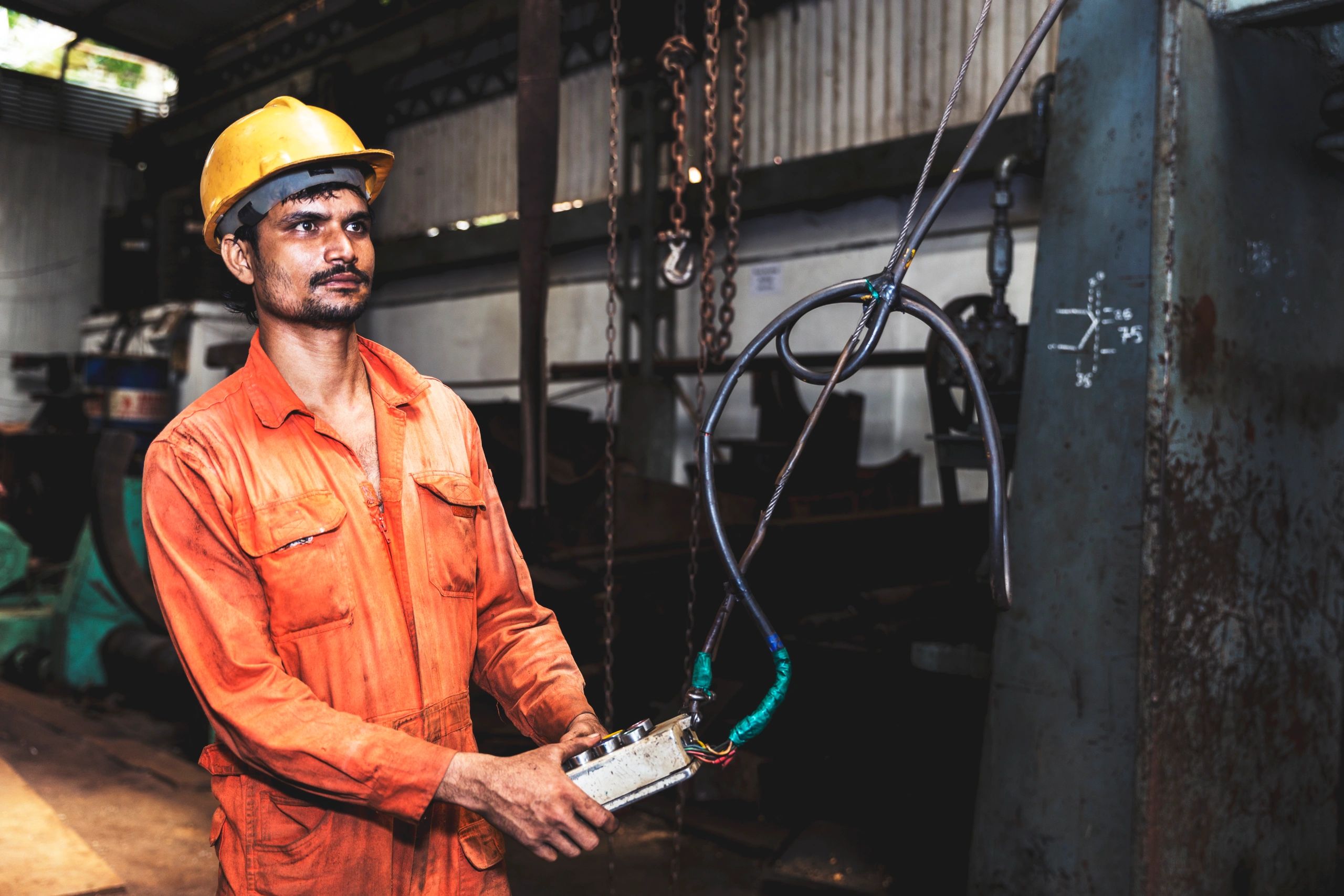 Technician operating an overhead crane with a wired controller